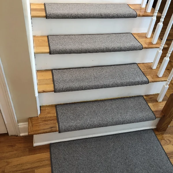 Grey fabric stair treads with dark edging on natural wood steps.